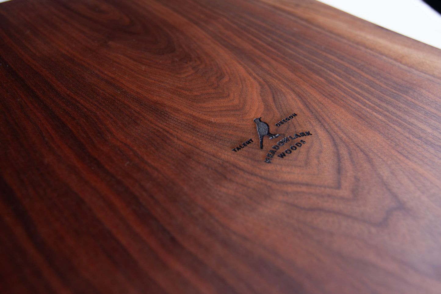 A close up of the meadowlark logo inscribed into a piece of walnut with beautiful figured grain