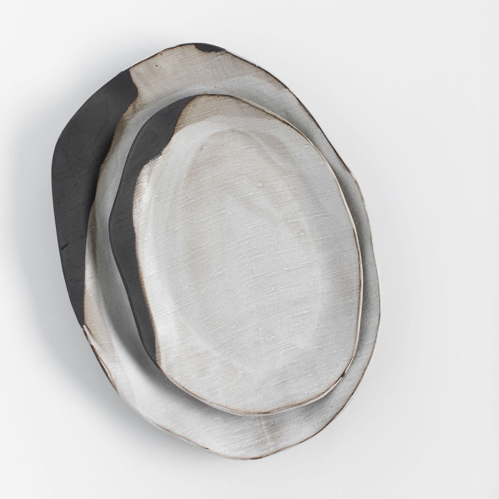 Overhead view of two nested Rustic Pour Over oval platters showing their organic shapes and contrasting glaze.