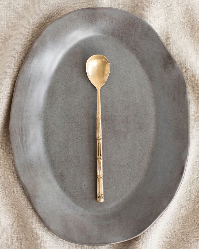 Charcoal platters and gold spoon on warm oatmeal linen