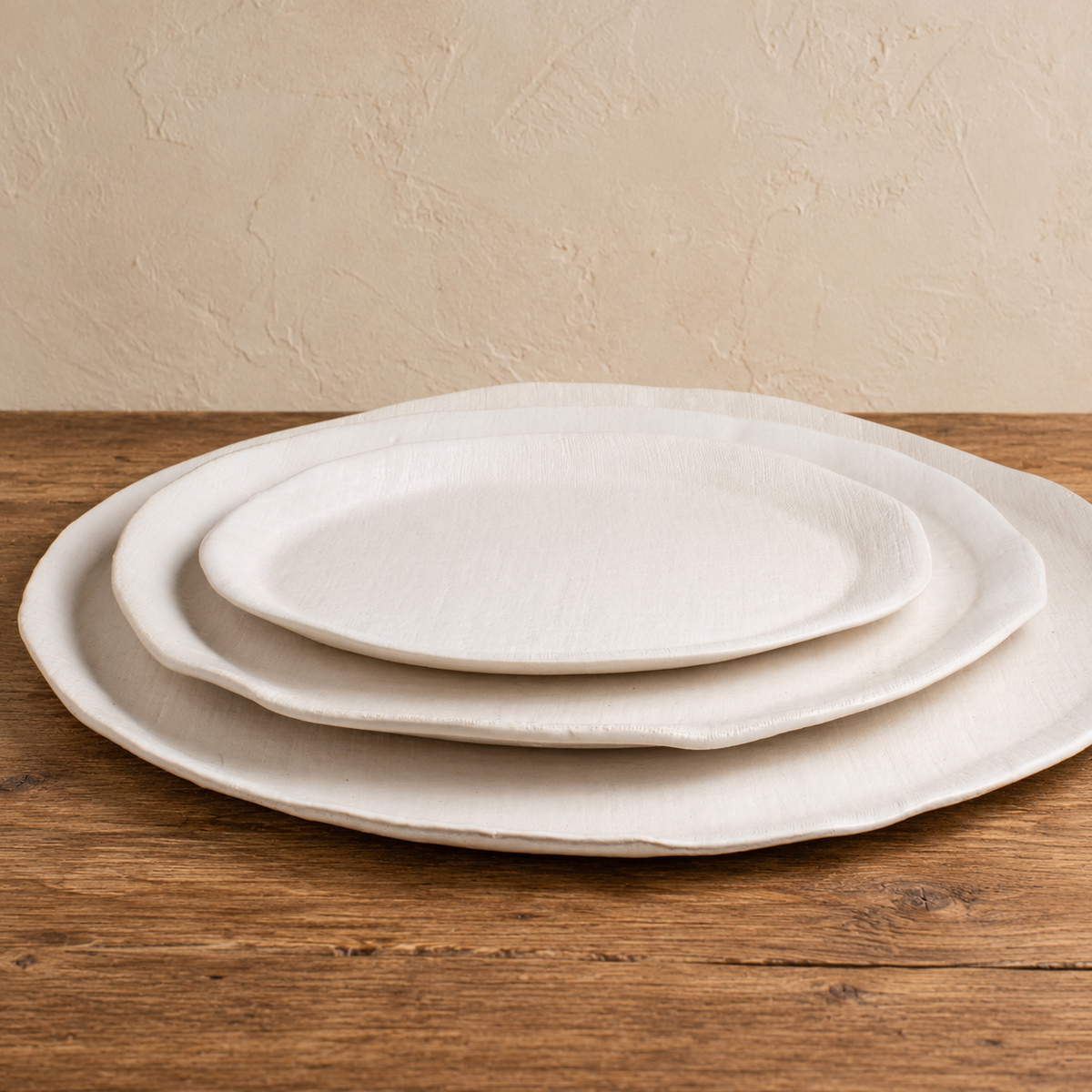 Three White Matte oval stoneware platters stacked to show their different sizes and softly irregular rims.