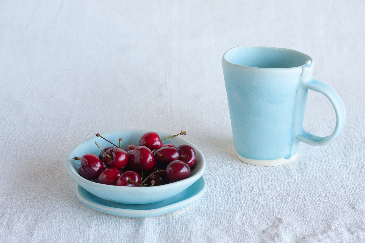 Ceramic collander, plate and mug with fresh cherries