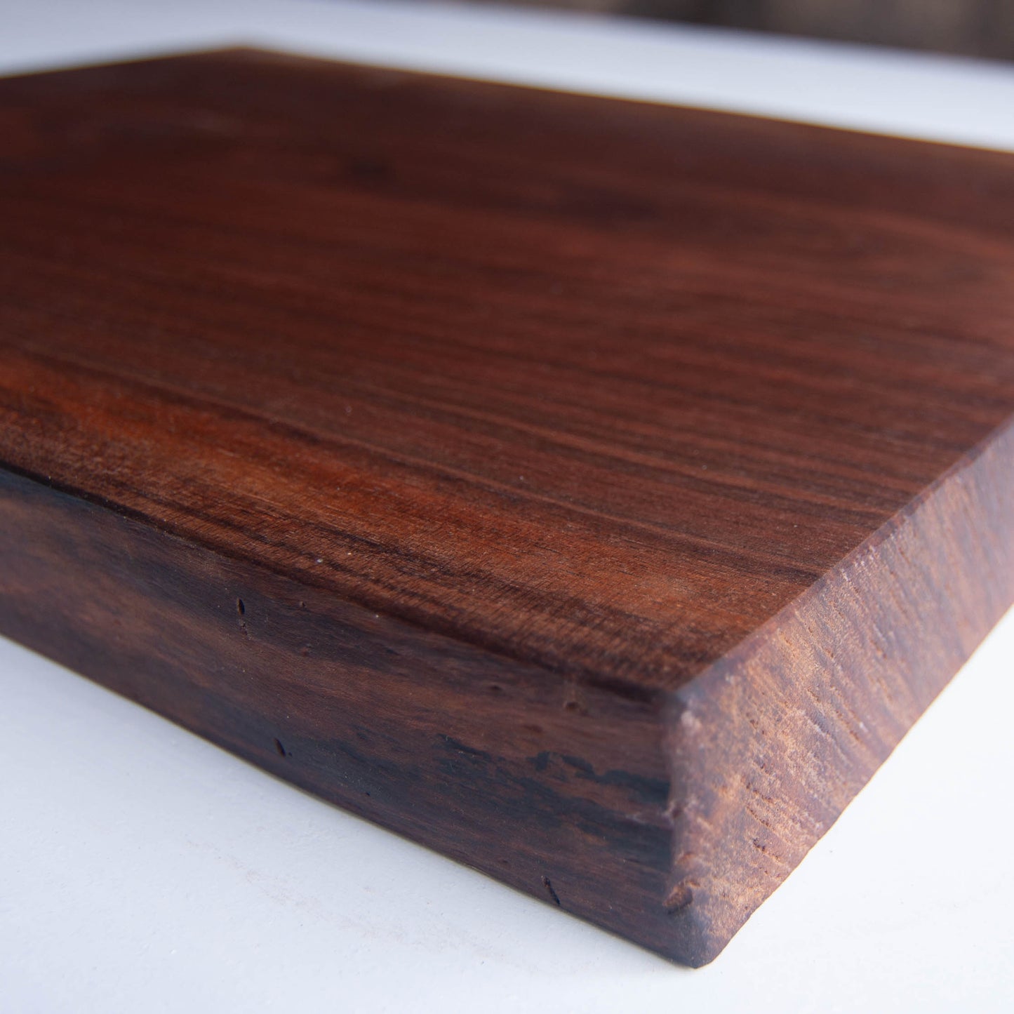 A close up of the corner of a walnut cutting board showing the natural edges of the board