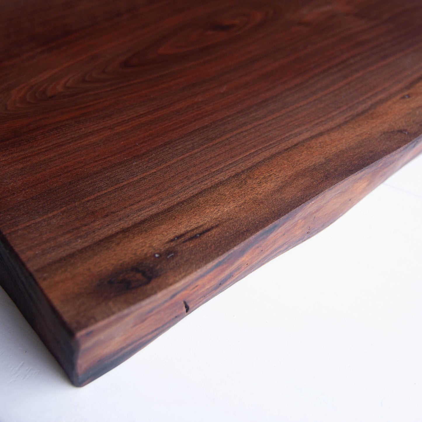 A close up of a walnut cutting board showing the figured grain and live edge