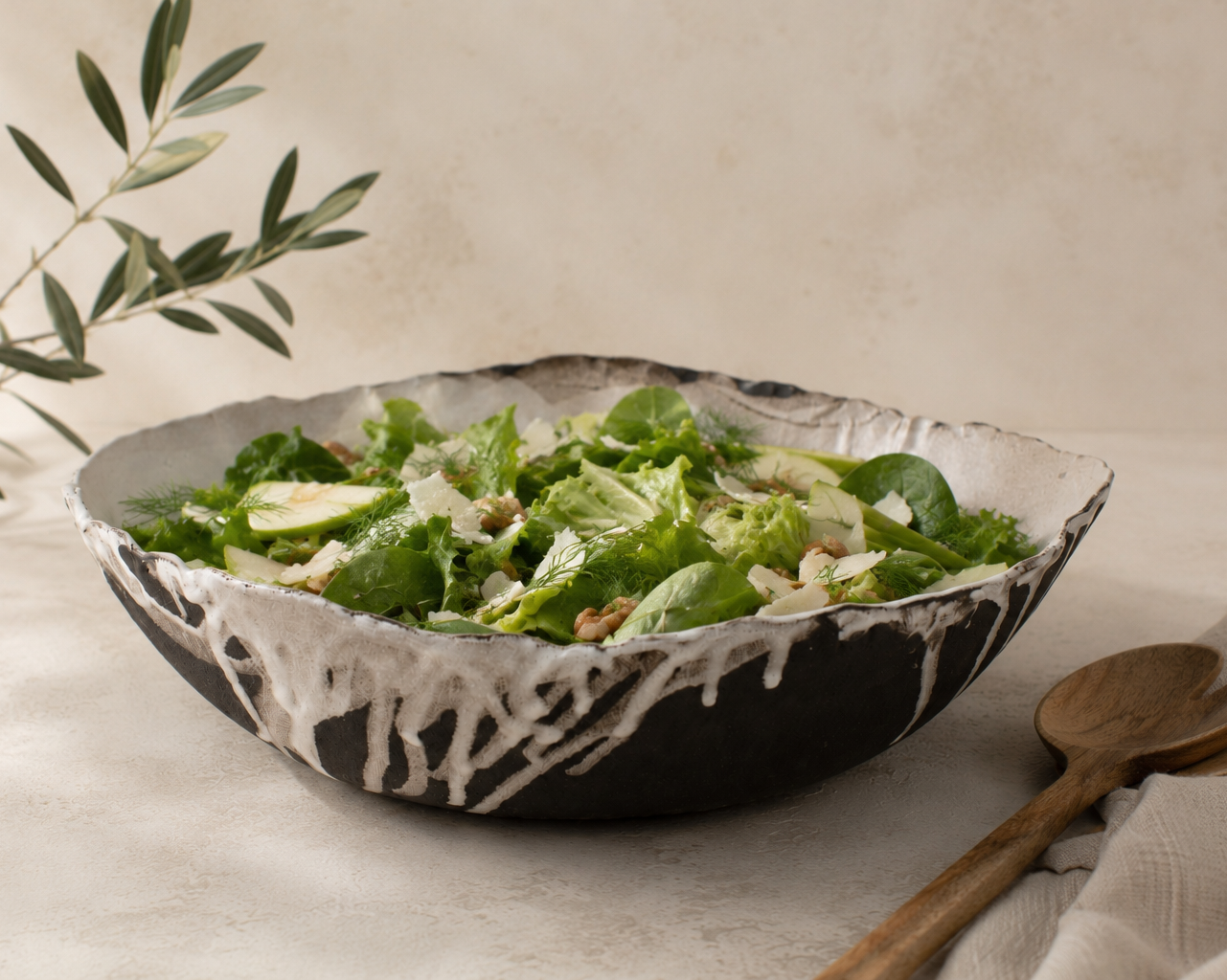 Bowl of salad with a wooden spoon on a light surface
