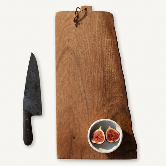 Number 412 California Black Honey Oak serving board with a leather loop, styled with a knife and a bowl of figs on a porcelain-white background.