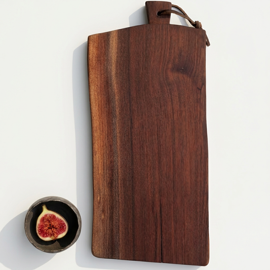 Number 306 Orchard Black Walnut serving board with leather loop, styled beside a bowl holding a fig on a porcelain-white background.
