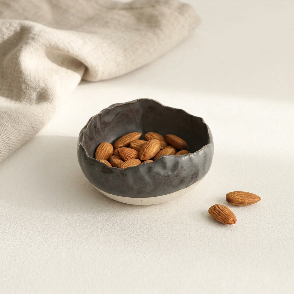 Charcoal Shino Mise en Place Bowl with toasted almonds, styled on porcelain with natural linen.