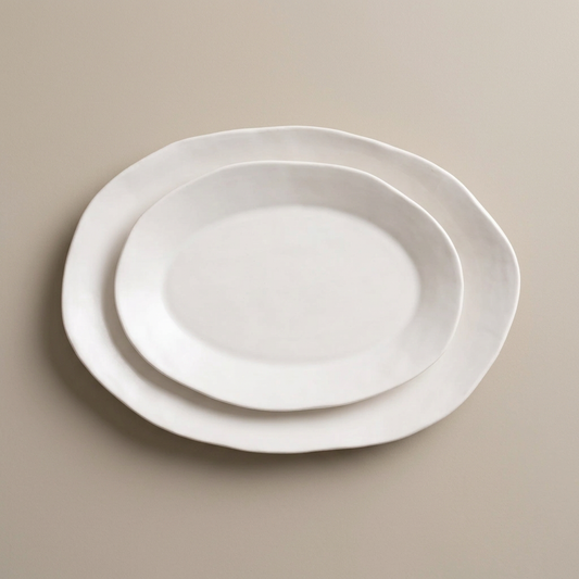 Two nested Modern White Matte oval serving platters on a warm-stone background.