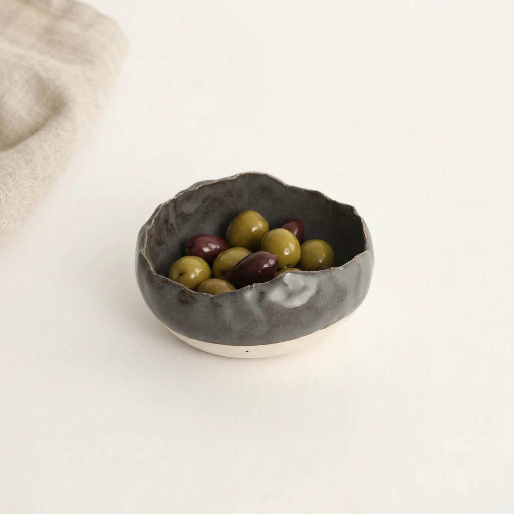 Charcoal Shino Mise en Place Bowl holding olives on a porcelain background.