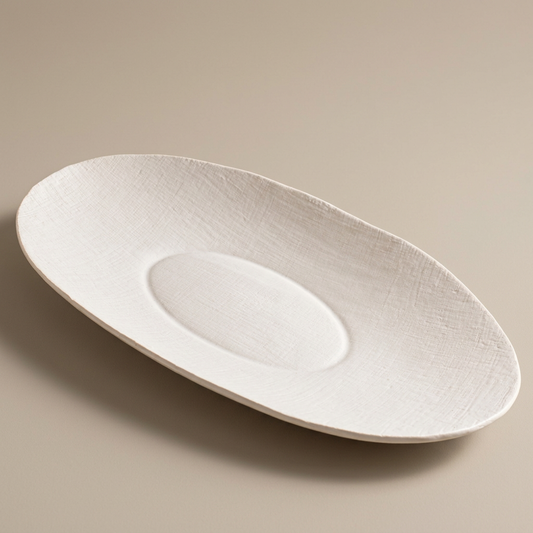 White Linen oval ceramic serving bowl on a seamless warm-stone background.